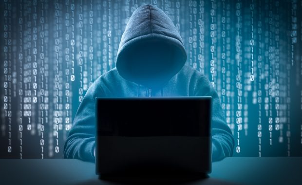 hooded hacker using a laptop